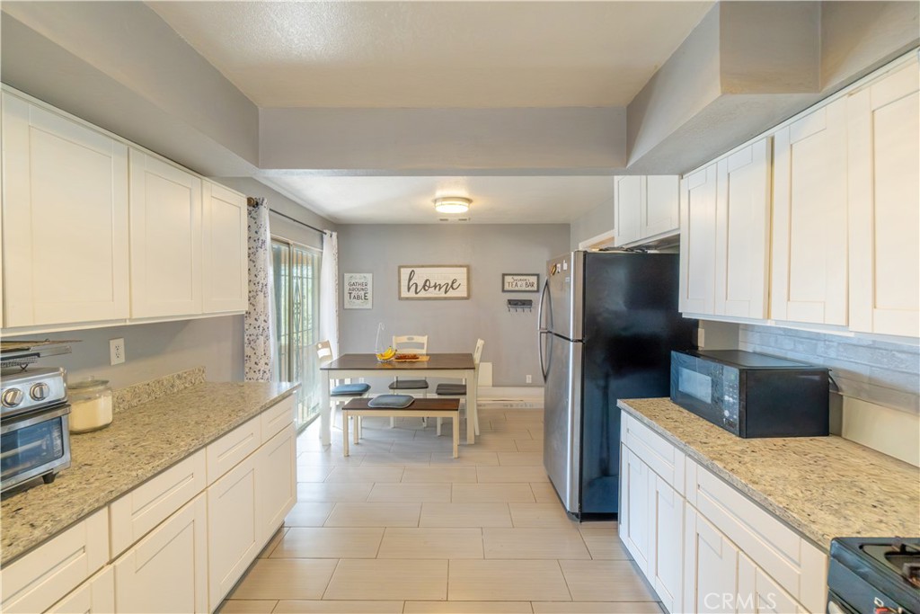 16403 Seneca Road Victorville, CA 92395 - Photo 11 of 47 a kitchen with stainless steel appliances granite countertop a refrigerator a stove and a sink with cabinets