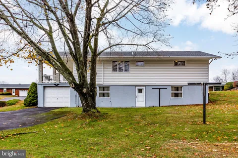 a front view of house with yard and trees in the background