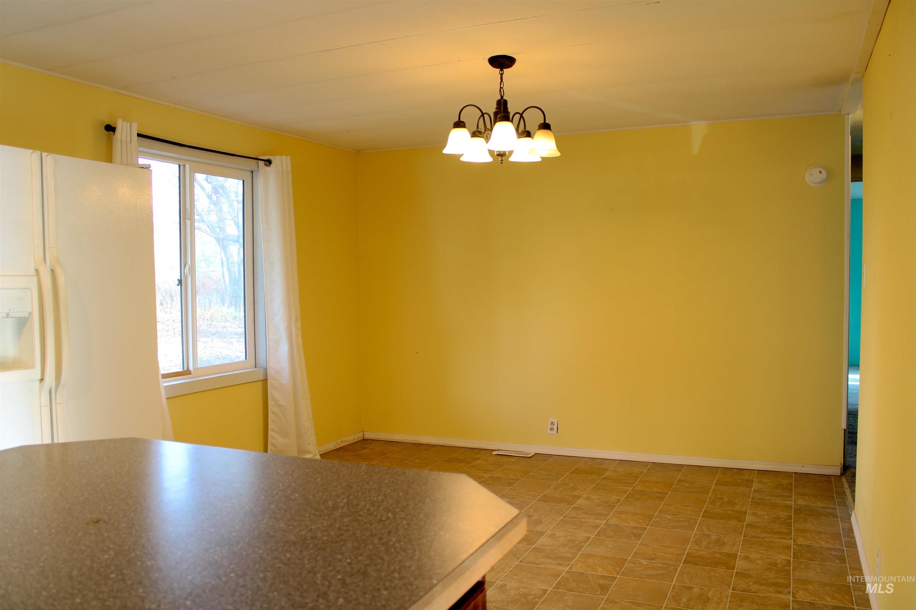 15881 Purple Sage Road, Unit 3 Caldwell, ID 83607 - Photo 11 of 29 Unfurnished dining area featuring baseboards and a chandelier