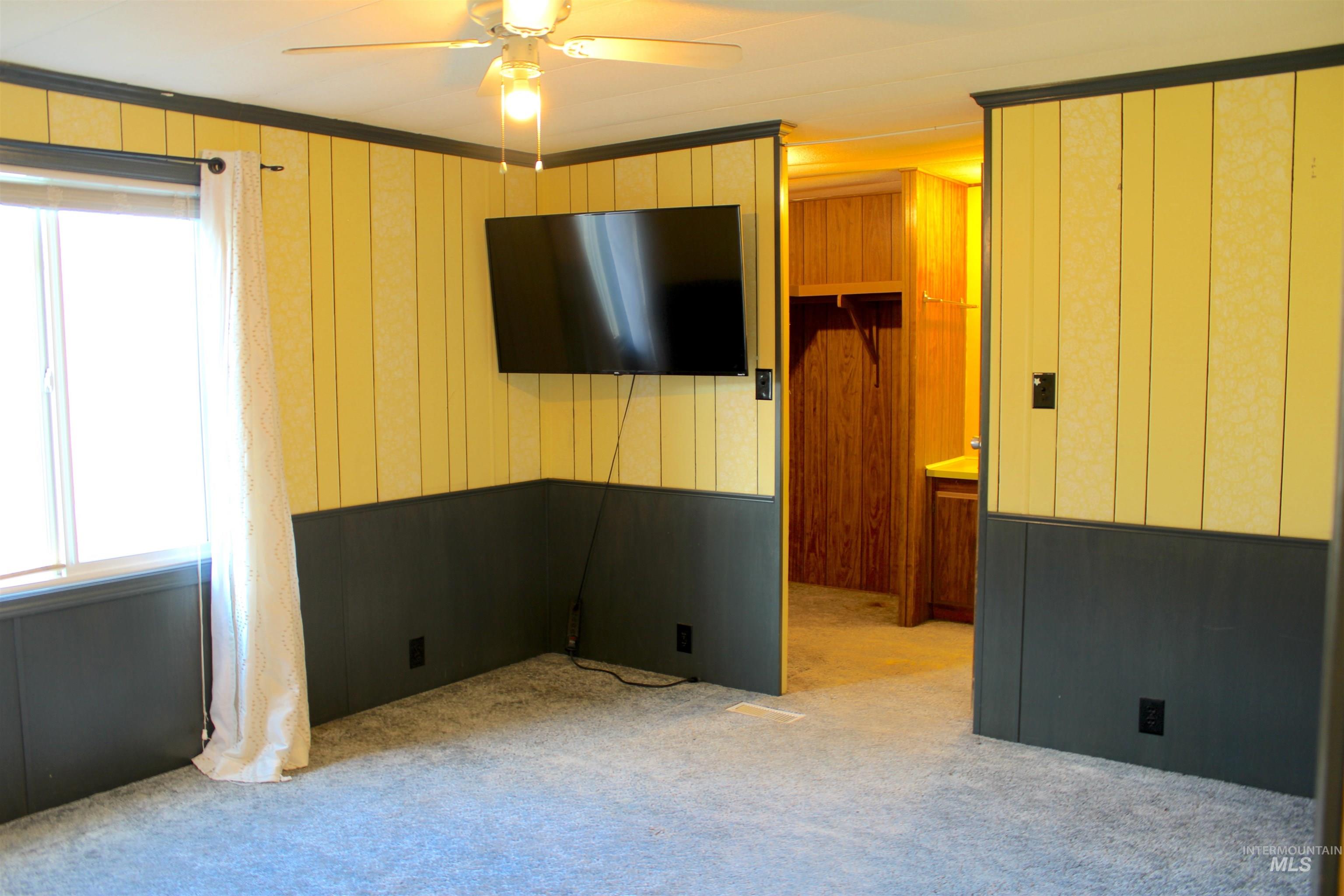 15881 Purple Sage Road, Unit 3 Caldwell, ID 83607 - Photo 21 of 29 Carpeted spare room with wood walls and a ceiling fan