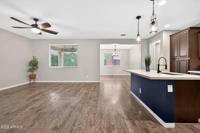 a large kitchen with stainless steel appliances a large counter top a sink and wooden floor