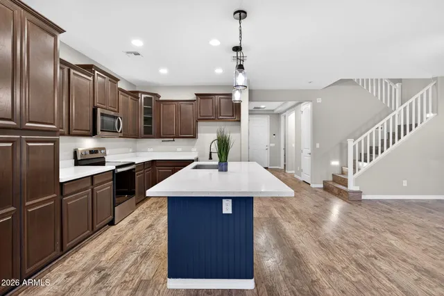 a kitchen with kitchen island granite countertop wooden floors wooden cabinets a center island and stainless steel appliances