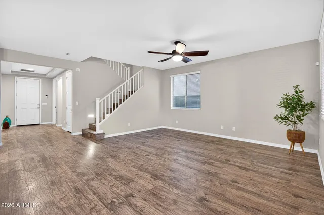 a view of an empty room with wooden floor and a chandelier fan