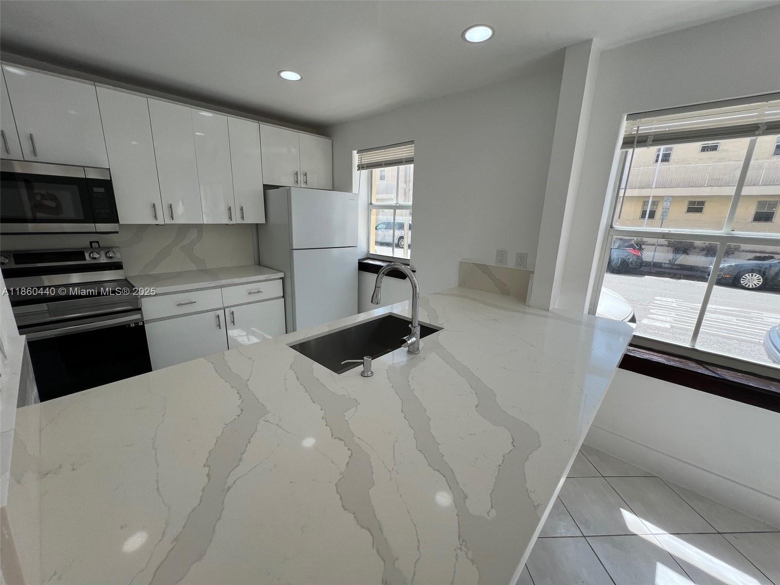 1308 Drexel Avenue, Unit 103 Miami Beach, FL 33139 - Photo 16 of 37 a kitchen with stainless steel appliances a refrigerator and a stove top oven