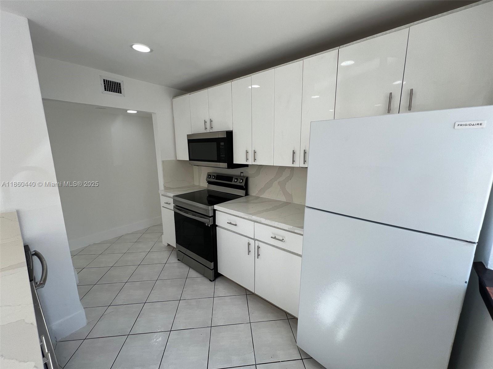 1308 Drexel Avenue, Unit 103 Miami Beach, FL 33139 - Photo 21 of 37 a kitchen with white cabinets and white appliances