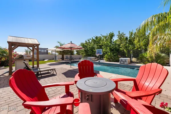 a view of swimming pool with lawn chairs and plants