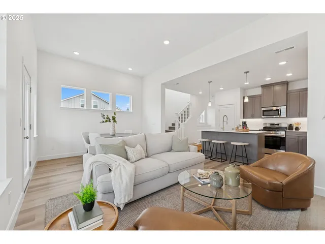 a living room with furniture potted plant and kitchen view
