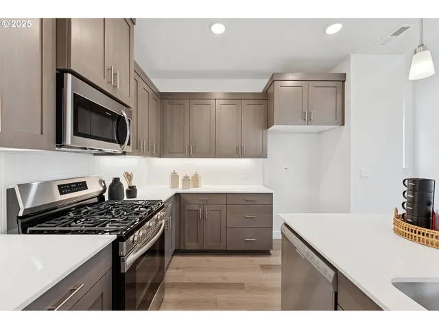 a kitchen with stainless steel appliances a sink dishwasher stove microwave and refrigerator