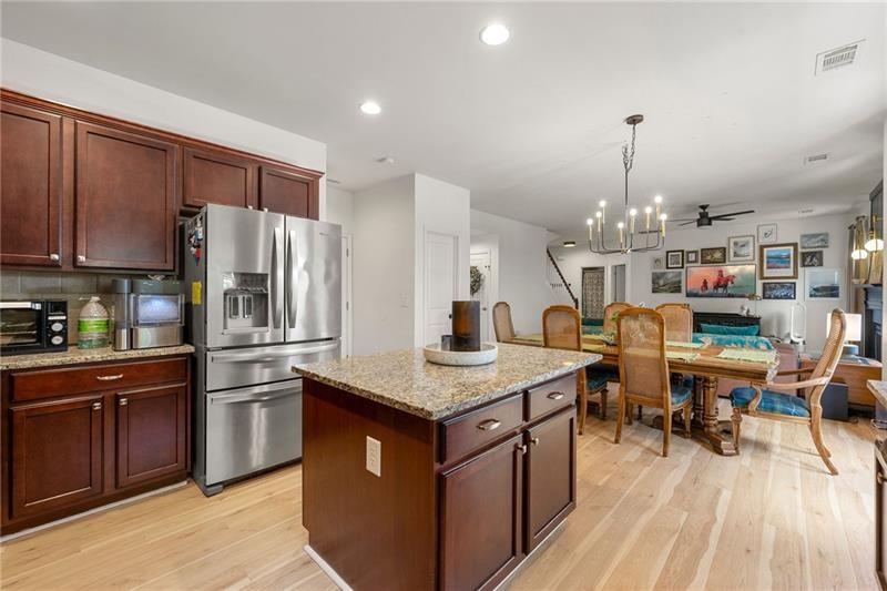 4970 Creekside Lane Powder Springs, GA 30127 - Photo 11 of 45 a kitchen with stainless steel appliances granite countertop a refrigerator a sink dishwasher a stove and a dining table with wooden floor