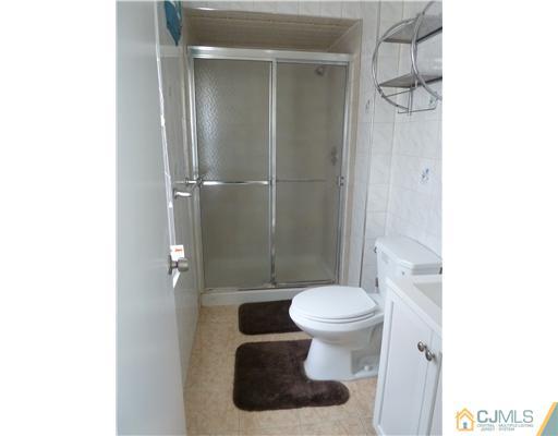 4 Paddock Court Edison, NJ 08820 - Photo 16 of 23 a white toilet sitting next to a bathroom sink and a shower