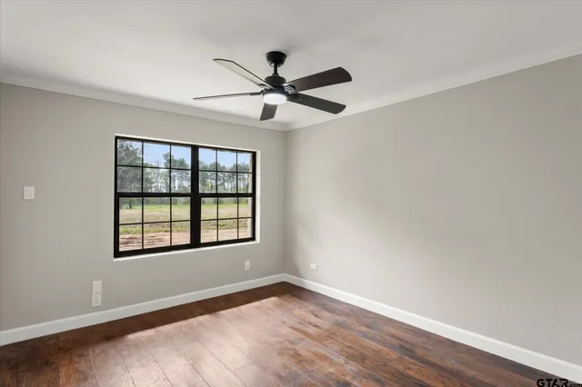 a view of an empty room with a window and wooden floor