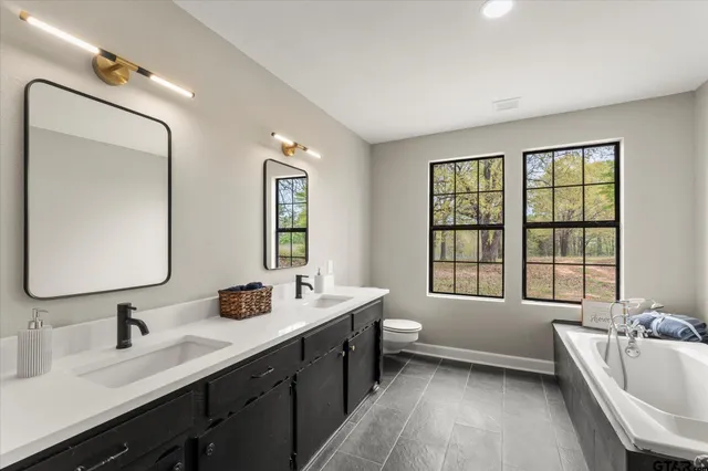 a bathroom with a tub double sink window and mirror