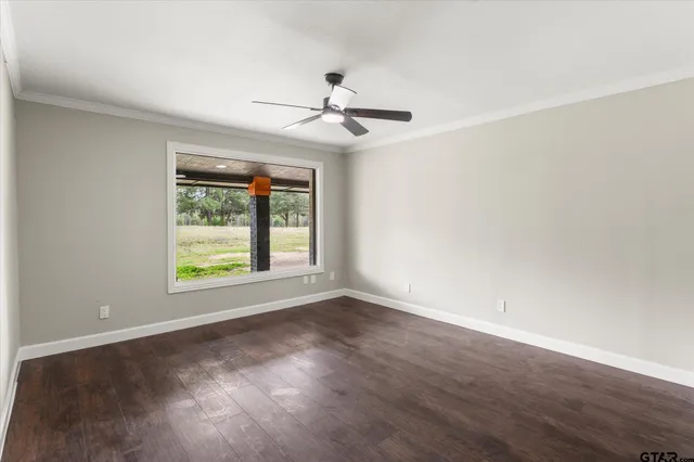 an empty room with wooden floor ceiling fan and windows