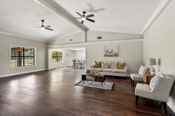 an empty room with wooden floor ceiling fan and windows