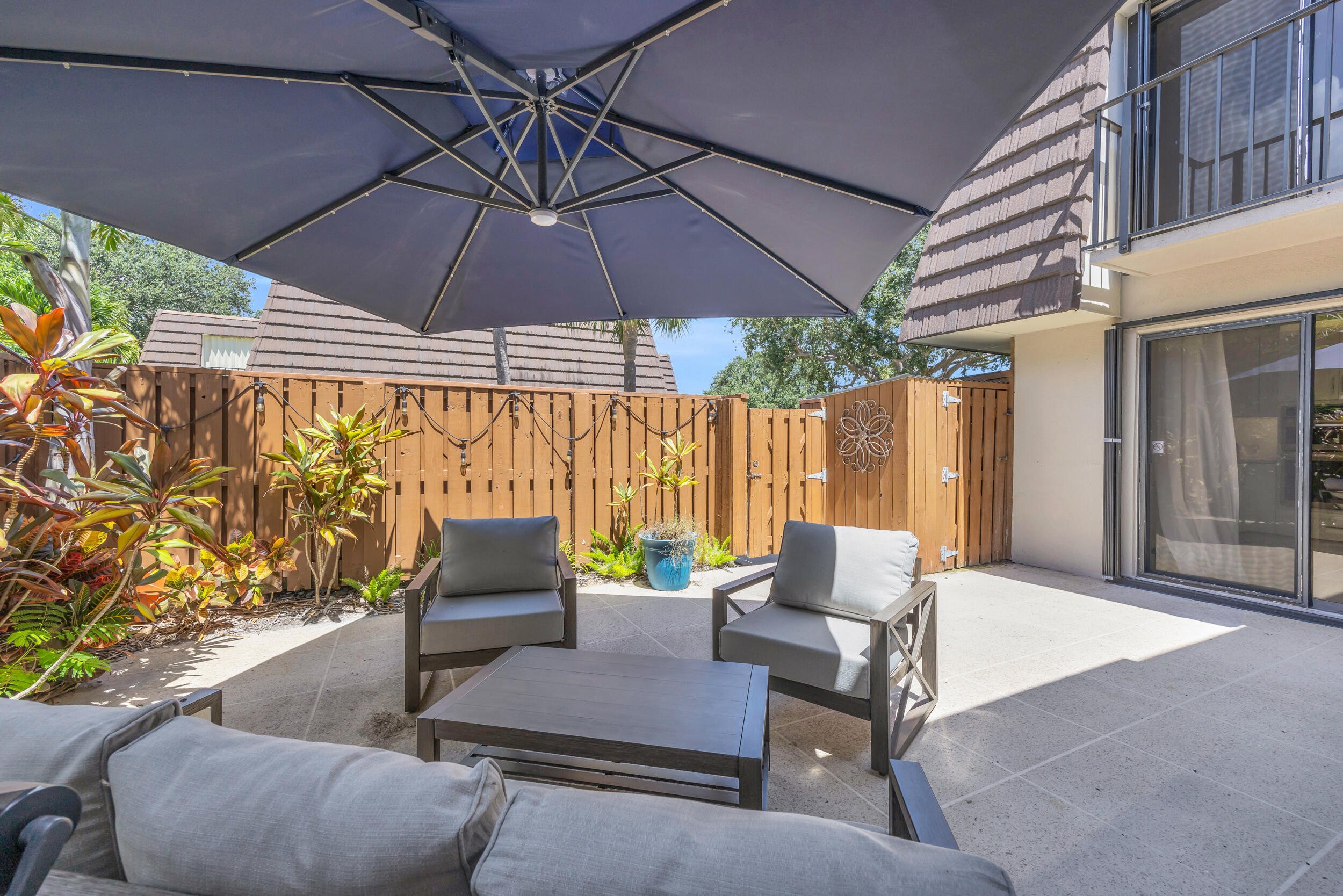 1208 12th Court Jupiter, FL 33477 - Photo 14 of 31 a patio with a table and chairs under an umbrella