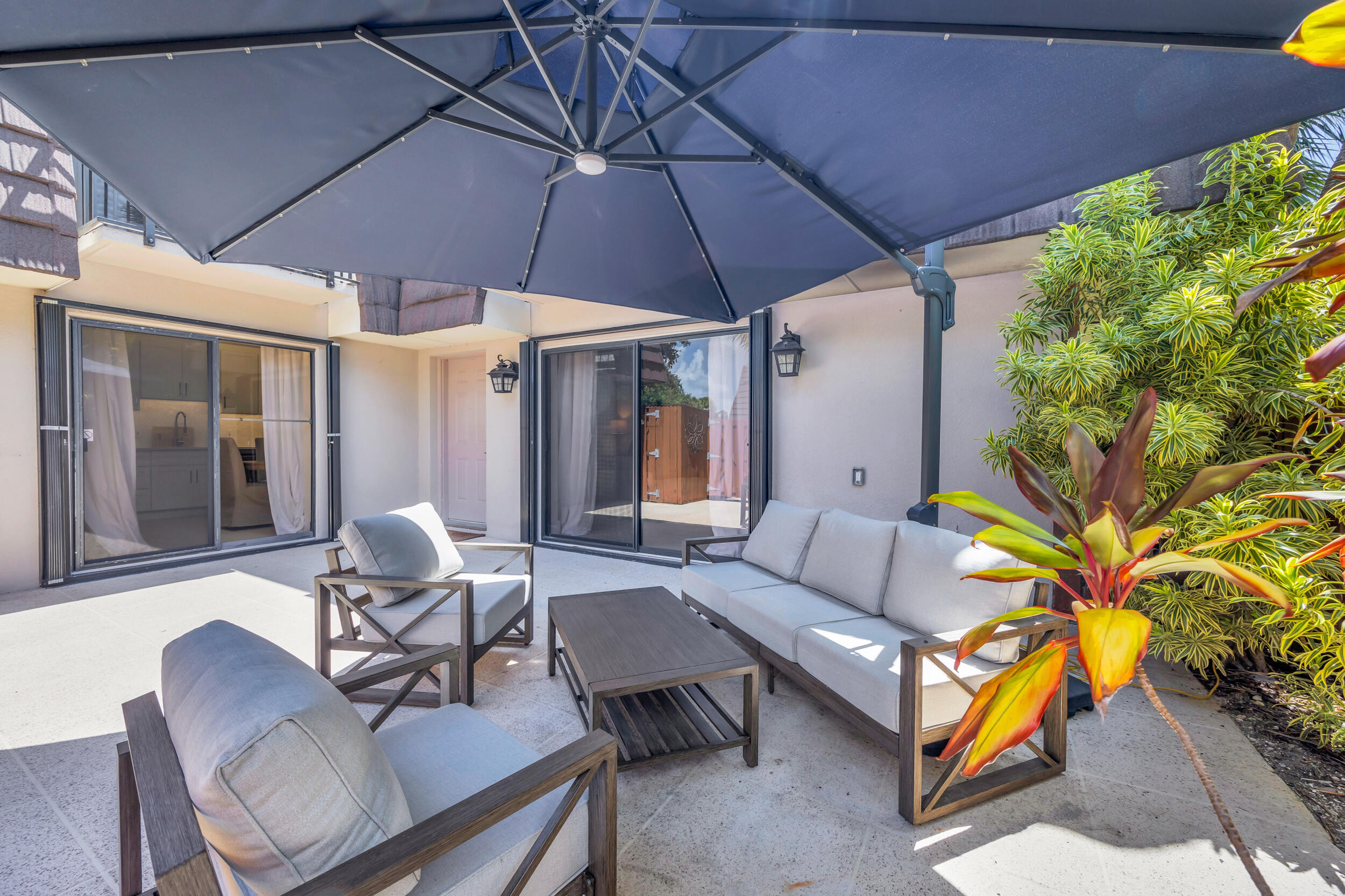 1208 12th Court Jupiter, FL 33477 - Photo 15 of 31 a patio with patio a table and chairs under an umbrella