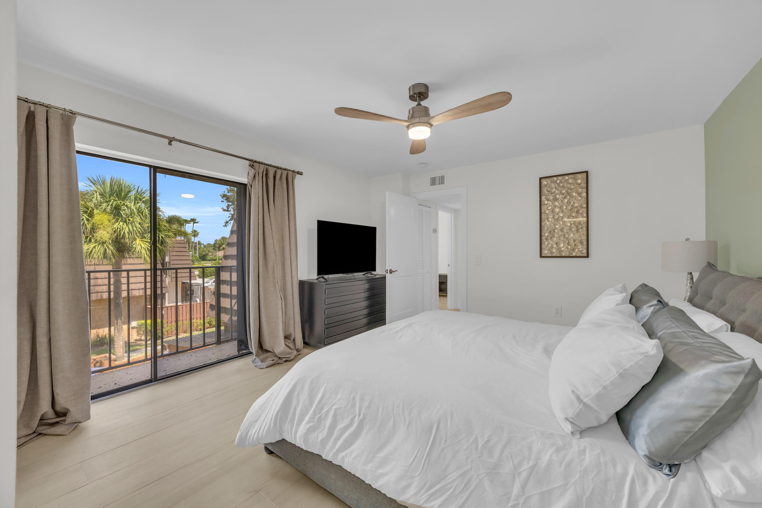 1208 12th Court Jupiter, FL 33477 - Photo 18 of 31 a bedroom with a balcony a bed and a flat screen tv
