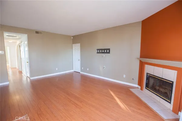 a view of an empty room with wooden floor fireplace and a window