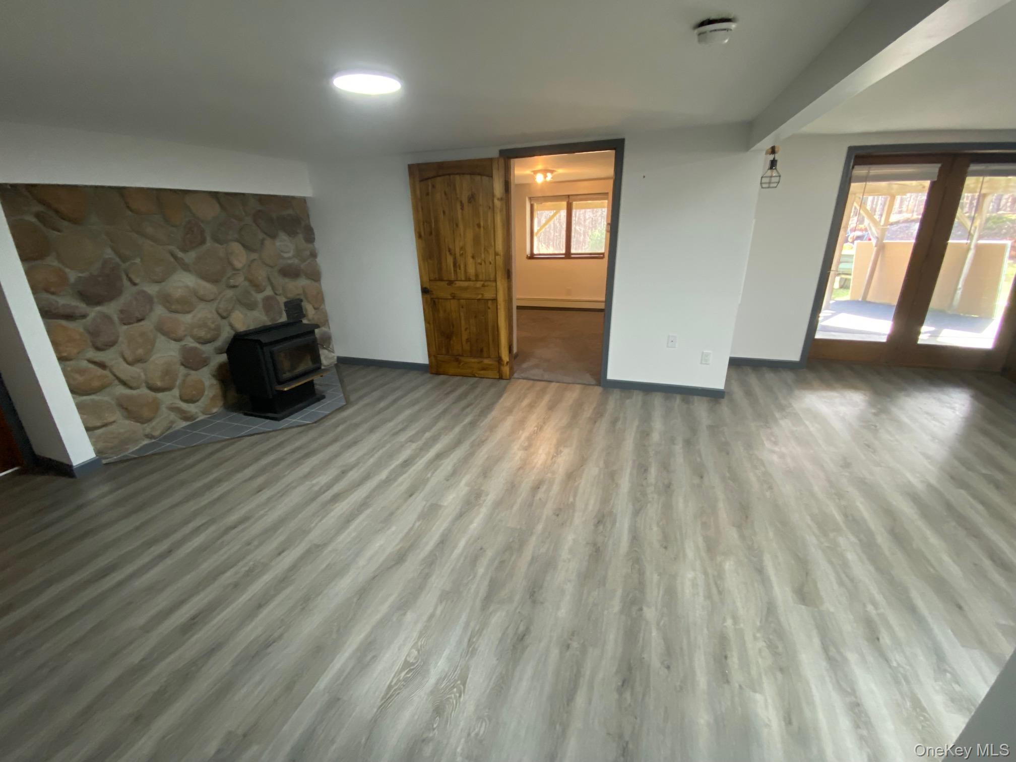 315 Upper Road, Unit LOWR Middletown, NY 10940 - Photo 5 of 9 Unfurnished living room featuring light wood-type flooring, a wood stove, and a wealth of natural light