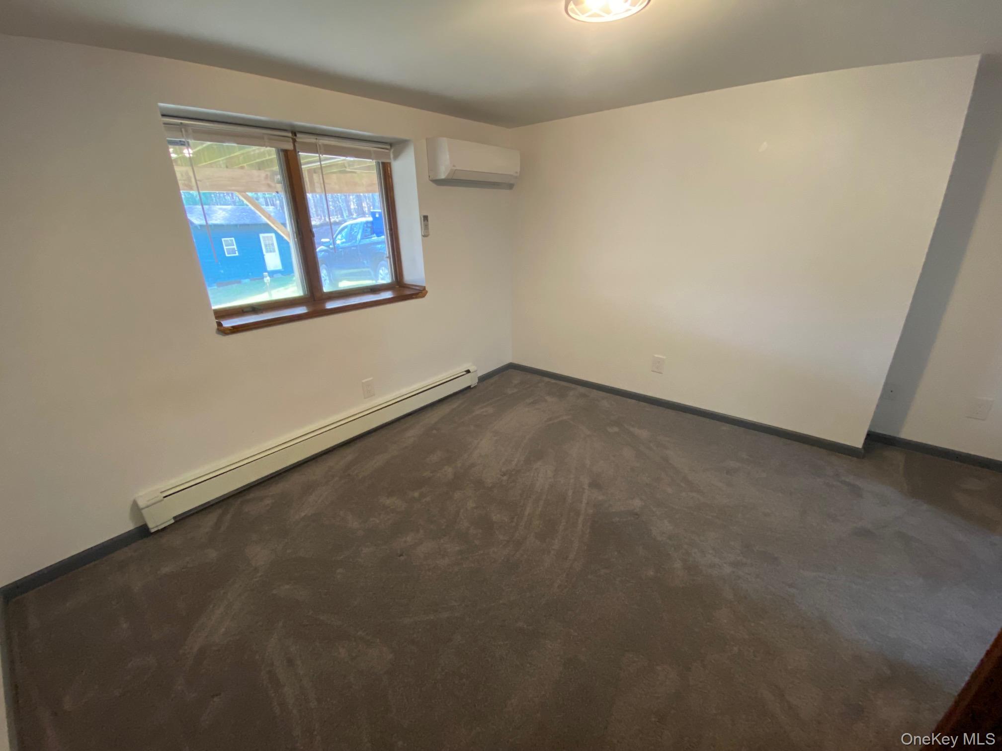 315 Upper Road, Unit LOWR Middletown, NY 10940 - Photo 6 of 9 Bedroom featuring a wall mounted air conditioner, dark colored carpet, and a baseboard radiator