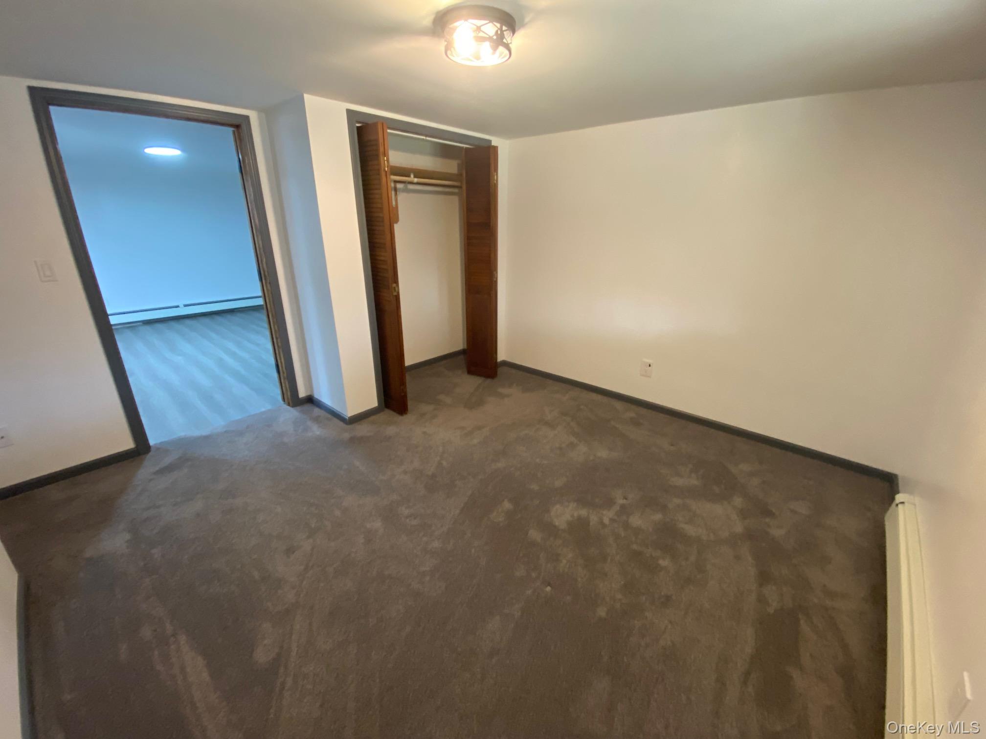 315 Upper Road, Unit LOWR Middletown, NY 10940 - Photo 7 of 9 Unfurnished bedroom with dark colored carpet, a baseboard radiator, and a closet