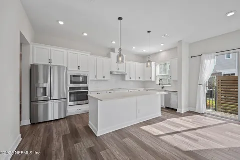 a kitchen with kitchen island white cabinets and stainless steel appliances