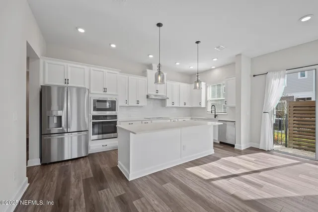 a kitchen with kitchen island white cabinets and stainless steel appliances