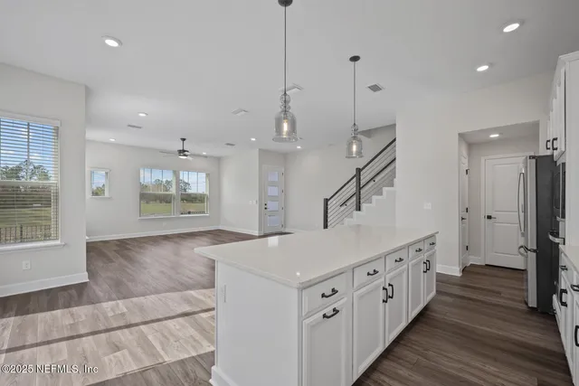 a open kitchen with kitchen island a sink appliances and a wooden floor