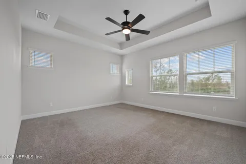 an empty room with windows and ceiling fan