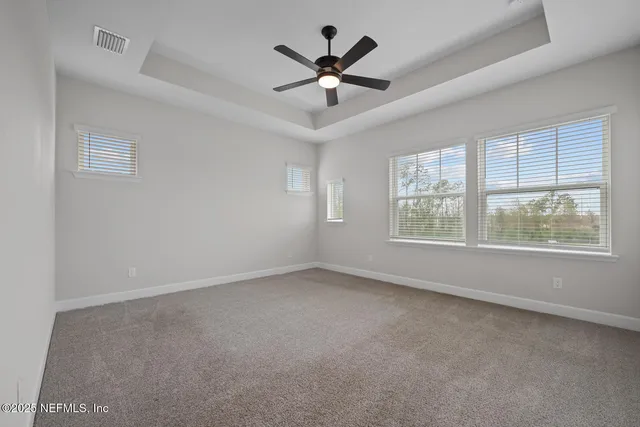 an empty room with windows and ceiling fan