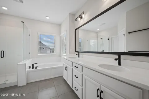 a bathroom with a double vanity sink and mirror with bathtub