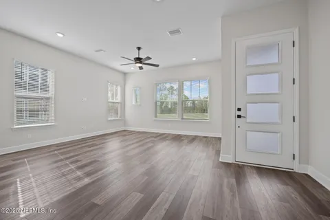a view of an empty room with a window and wooden floor