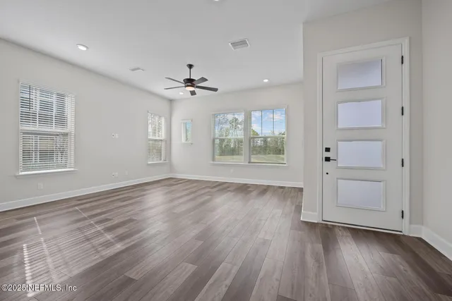 a view of an empty room with a window and wooden floor