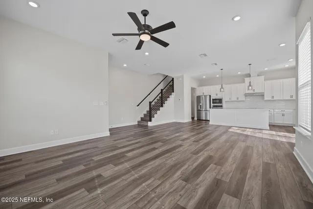 a view of a room with wooden floor and ceiling fan