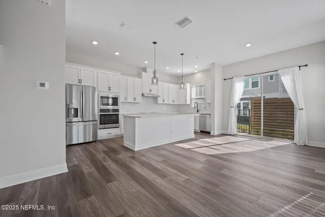 a view of kitchen with wooden floor and electronic appliances
