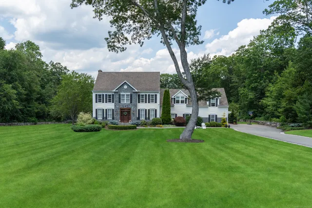 a front view of a house with garden and trees