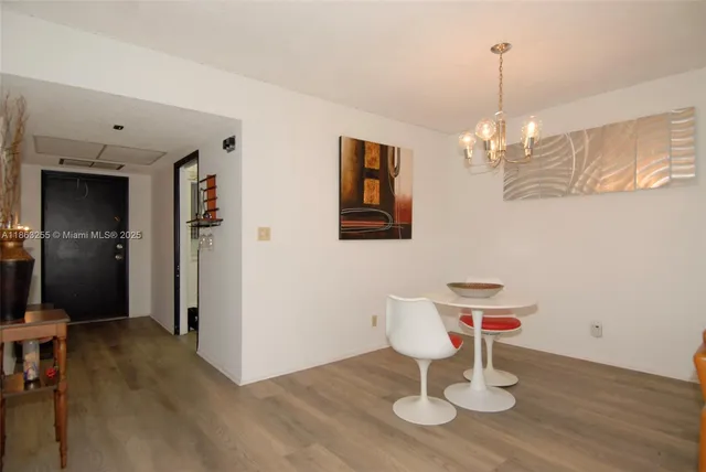 a dining room with wooden floor a chandelier a wooden table and chairs