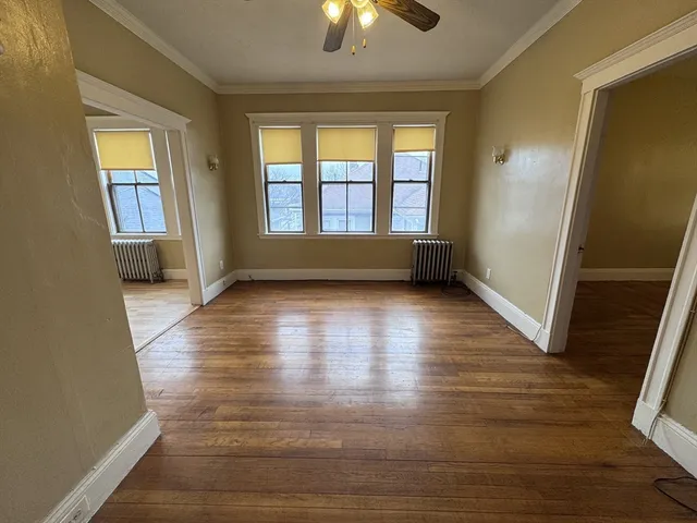 a view of empty room with wooden floor and fan