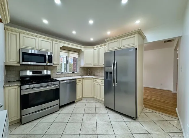 a kitchen with stainless steel appliances granite countertop a refrigerator and a stove top oven