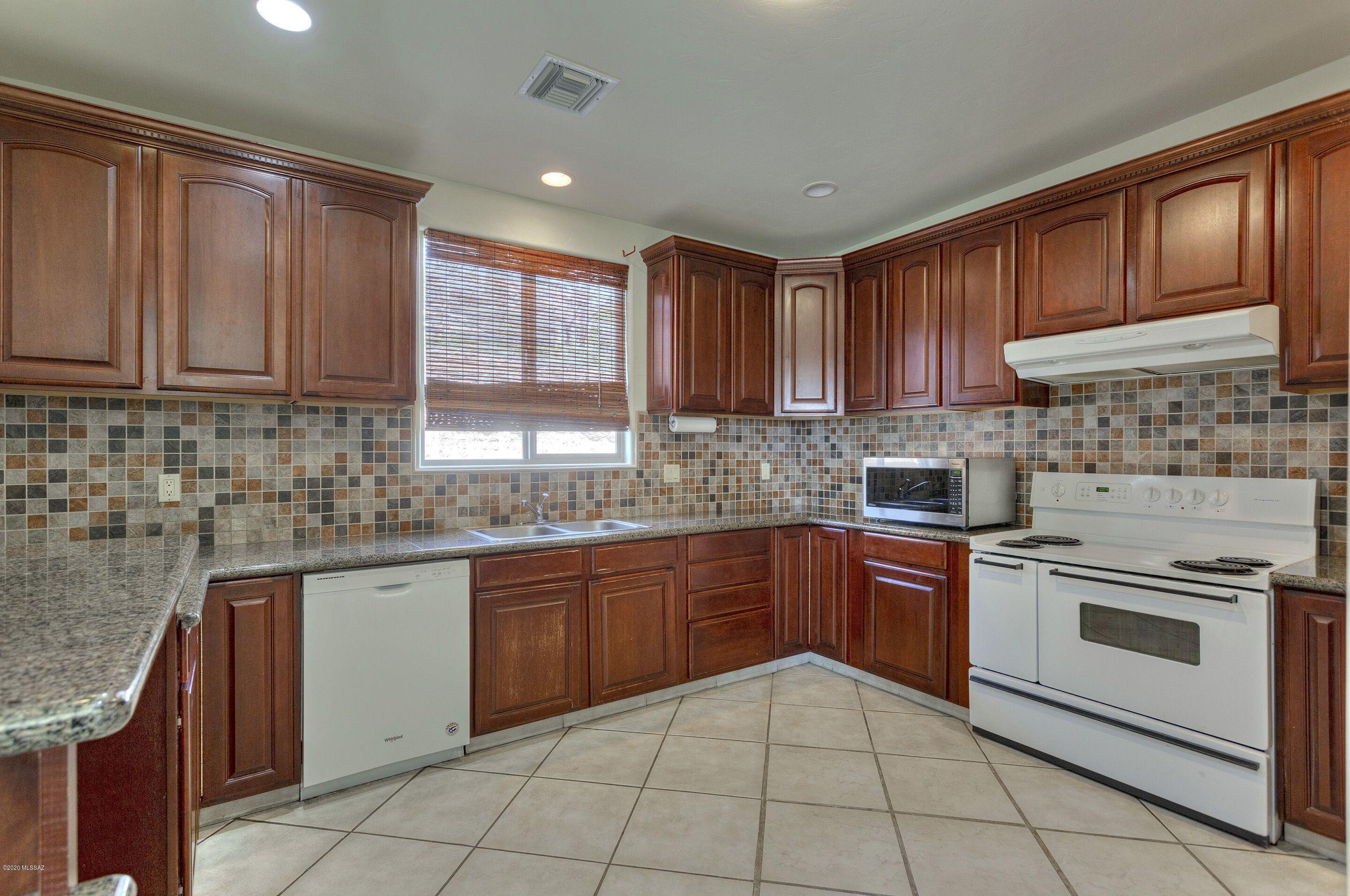 1253 Calle Tubatana Rio Rico, AZ 85648 - Photo 6 of 22 a kitchen with stainless steel appliances granite countertop wooden cabinets granite counter tops and a stove top oven