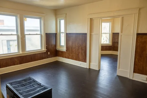 an empty room with wooden floor and windows