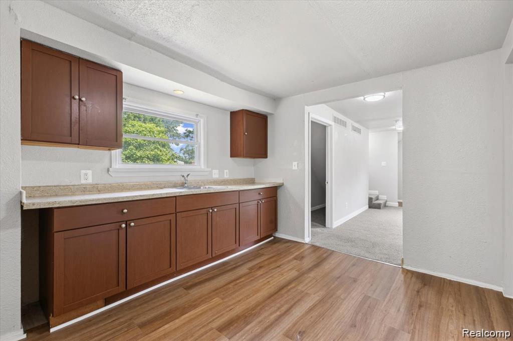 3140 Moore Street Inkster, MI 48141 - Photo 6 of 18 Kitchen area featuring wood-finish flooring, ample cabinetry, and a countertop with an integrated sink