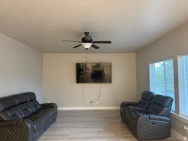 437 North 650 E Street Springville, UT 84663 - Photo 5 of 11 Spacious living area featuring light wood-finish flooring, a ceiling fan with integrated lighting, and multiple windows with horizontal blinds