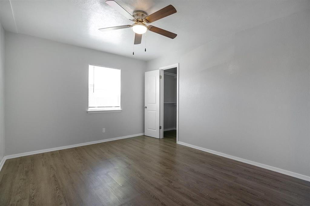 307 Rose Street, Unit 311C Arlington, TX 76010 - Photo 7 of 10 an empty room with wooden floor ceiling fan and window