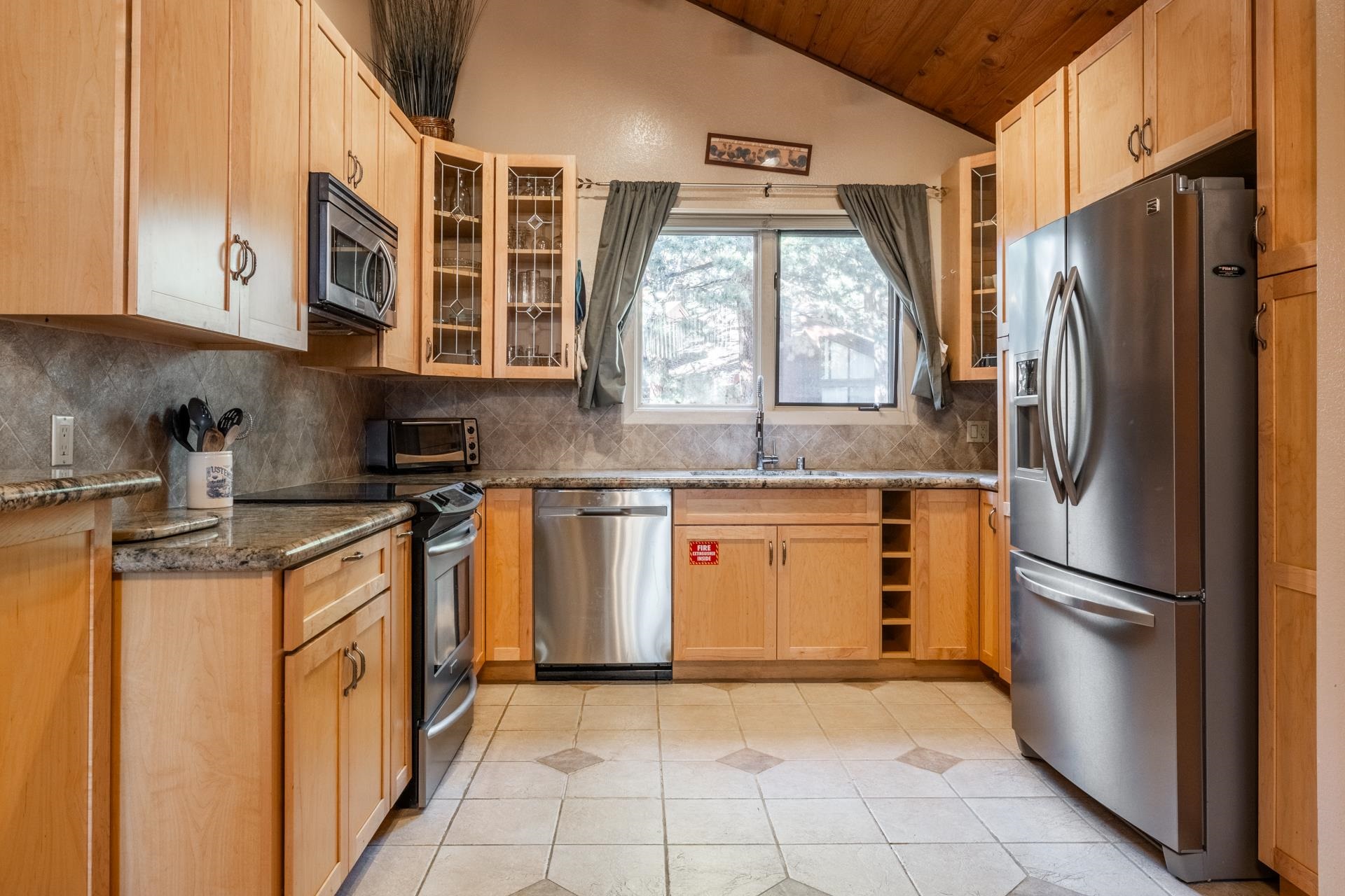 2112 Meridian Boulevard, Unit 7 Mammoth Lakes, CA 93546 - Photo 7 of 33 Kitchen with lofted ceiling, dark stone counters, stainless steel appliances, backsplash, and light tile patterned floors