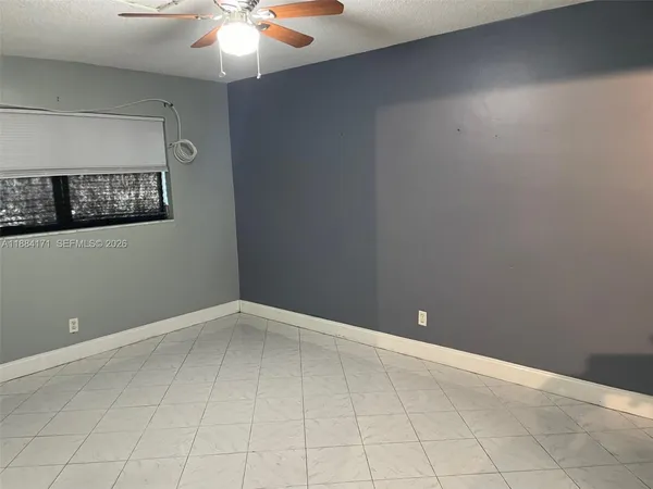 a view of an empty room with chandelier fan