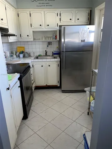 a kitchen with a sink a refrigerator and cabinets