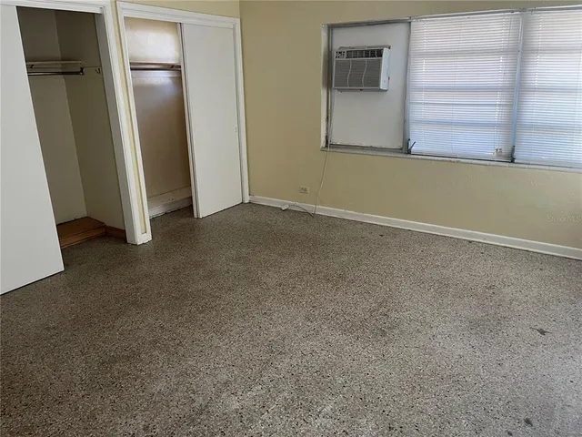 a view of an empty room with closet and a window