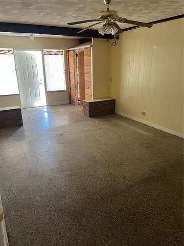 en empty room with windows and ceiling fan