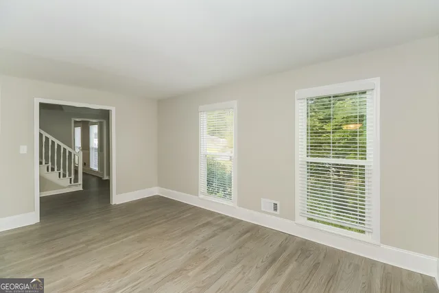 a view of an empty room with wooden floor and a window